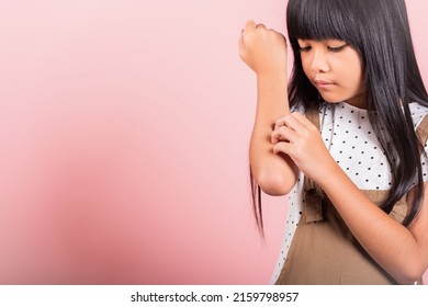 Asian Little Kid 10 Years Old Scratching Itch Arm From A Mosquito Bite At Studio Shot Isolated On Pink Background, Portrait Of Happy Child Girl Dermatitis And Scabies, Allergy Symptoms, Malaria Day