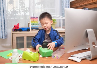 Asian Little Kid Making Art And Craft Project Using Computer Alone During His Online Lesson At Home, Kindergarten Closed During The Covid-19 Health Crisis, Distance Learning, Homeschooling Concept