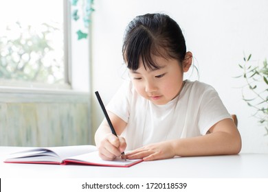 Asian Little Kid Studying At The Table.