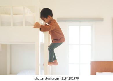 Asian Little Toddler Boy Is Trying To Climb Up The Ladder Of Bunk Bed In The Bedroom. Concept Of Childhood, Kid Development, Physical Activity, Muscle, Playful, Learning, Life Skill For Children.