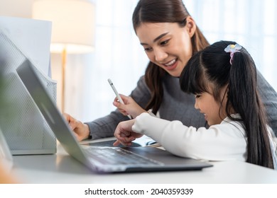 Asian Little Young Girl Kid Learning Online Class At Home With Mother. Preschool Child Use Laptop Computer Do Homework, Homeschool From School Teacher By Digital Remote Internet With Support From Mom.