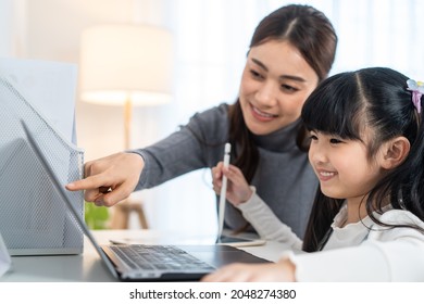 Asian Little Young Girl Kid Learning Online Class At Home With Mother. Preschool Child Use Laptop Computer Do Homework, Homeschool From School Teacher By Digital Remote Internet With Support From Mom.