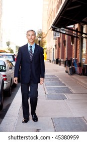 An Asian Looking Business Man Walking In A Street