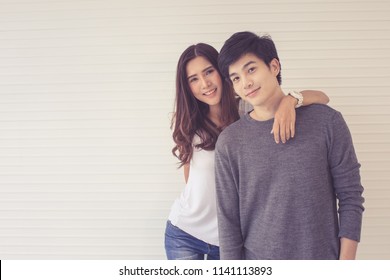 Asian lovely couple standing together with manner of love, beautiful girl hold around neck of handsome boy pose to camera, concept for lovers and lifestyle of modern adult.