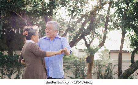 Asian Lovely Happy Senior Couple Grandfather And Grandmother Dancing Or Hugging Outside Of Home. Joyful Elderly Smiling Retired Lover Embracing Or Holding In Romantic Moment Of Love.