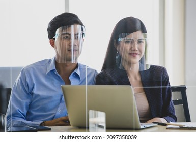 Asian Lover Married Couple Male And Female Husband And Wife Wearing Plastic Face Shield Sitting Together At Bank Office Counter With Glass Partition Waiting For Financial Service During Quarantine.