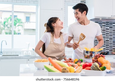 Asian lovers or couples cooking so funny together in kitchen with full of ingredient on table. Honeymoon and Happiness concept. Valentines day and Sweet home - Powered by Shutterstock