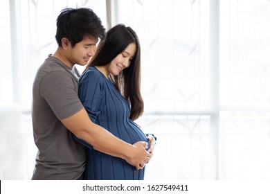 Asian lovers, they are happy. He touches the pregnant belly. - Shutterstock ID 1627549411