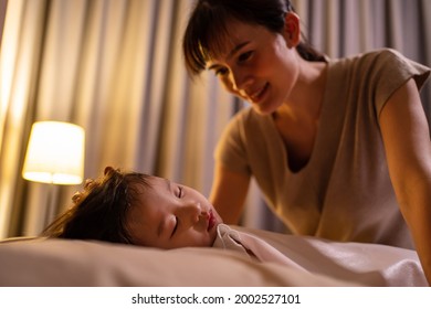 Asian Loving Beautiful Mother Take Care Asleep Young Comfortable Kid. Caring Parent Mom Put Blanket On Sleeping Little Small  Girl Daughter On Bed In Dark Bedroom At Night. Parenting Activity At Home.