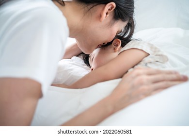 Asian loving beautiful mother take care asleep young comfortable kid. Caring parent mom put blanket on sleeping little small girl daughter on bed in the morning in bedroom. Parenting activity at home.