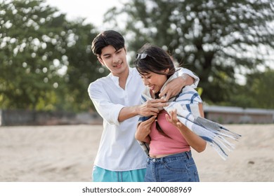 Asian loving boyfriend wrapped blanket on his girlfriend at the beach. Attractive young couple feel happy and enjoy spending leisure time at seaside enjoy holiday honeymoon trip in tropical sea island - Powered by Shutterstock