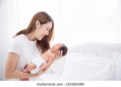 Asian Loving Mom Carying Of Her Newborn Baby At Home. Happy Mum Holding Sleeping Infant Child On Hands. Mother Hugging Her Little One Months Old Son.