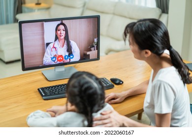 Asian Loving Mother And Little Girl Daughter Video Call With Doctor. Attractive Pediatrician Use Laptop For Virtual Online Give Consult And Treatment To Small Kid And Family For Health In Living Room.