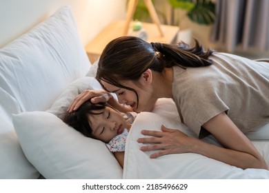 Asian loving mother take care of sleeping daughter in bedroom at home. Attractive happy family couple, mother puts blanket on comfortable asleep napping little baby kid on bed in the morning at house. - Powered by Shutterstock