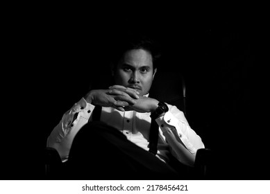 Asian Mafia Boss Sitting In A Chair With A Black Background