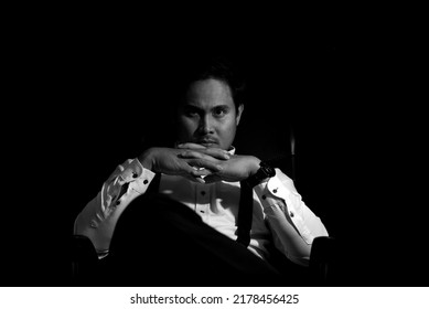 Asian Mafia Boss Sitting In A Chair With A Black Background