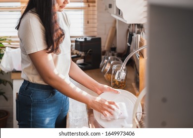 Asian maid housewife washing cleaning dishes in kitchen