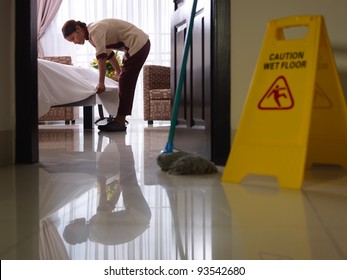 Asian Maid Tidying Up Bed And Cleaning Luxury Hotel Room