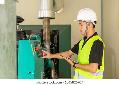 Asian maintenance technician checking technical data of water pressure control system equipment in factory.