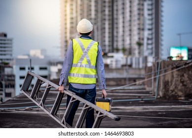 Asian maintenance worker man with safety helmet and green vest carrying aluminium step ladder and tool box at construction site. Civil engineering, Architecture builder and building service concepts - Shutterstock ID 1464693803