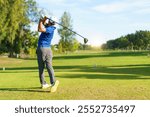 Asian male amateur golfer is enjoy playing golf at golf course in morning, he is showing his beautiful swing during tee off. Man playing golf.