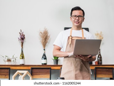 Asian Male Barista Cafe Owner Using Laptop In Cafe Business Inside Coffee Shop,looking And Smile At Camera.food And Drink Business Start Up.