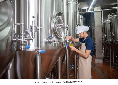 An Asian male brewer tests beer samples by pouring beer - Powered by Shutterstock