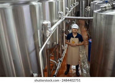 An Asian male brewer tests beer samples by pouring beer - Powered by Shutterstock