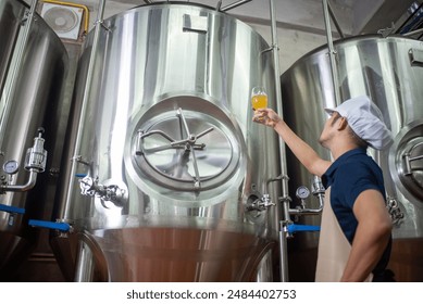 An Asian male brewer tests beer samples by pouring beer - Powered by Shutterstock