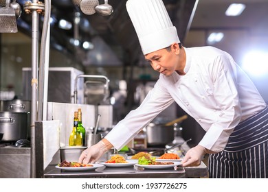 Chef asiático masculino que presenta el plato en la cocina. El concepto de restauración y de restauración.