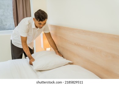 Asian Male Cleaning Staff Tidying Pillows On Bed In Hotel Room