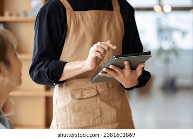 Asian male clerk taking orders at a cafe - Powered by Shutterstock