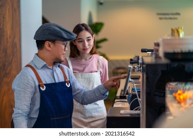 Asian male coffee shop manager teaching young woman staff working on digital tablet. Small business cafe and restaurant owner instruct part time employee preparing service to customers before opening - Shutterstock ID 2021316542