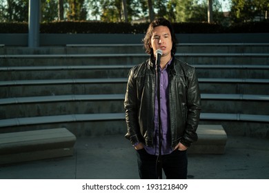 Asian Male Comedian With Microphone Doing Stand Up With No Audience In Empty Theatre Amphitheater With Funny Sad Look On Face