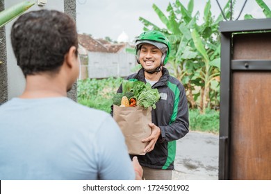 Asian Male Courier Delivering Grocery To Customer. Food Online Delivery