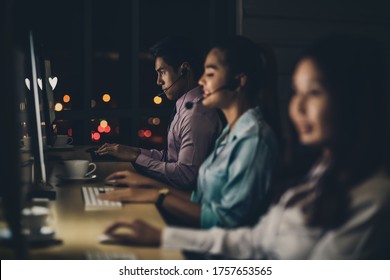 Asian male customer care service with business man smiling and working hard late in night shift at office,call center department,worker and overtime,7 days 24 hour,teamwork with colleagues for success - Shutterstock ID 1757653565