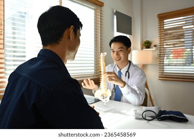 Asian Male doctor explaining the anatomical spine to a patient in the clinic, with Selective focus on patient. - Powered by Shutterstock