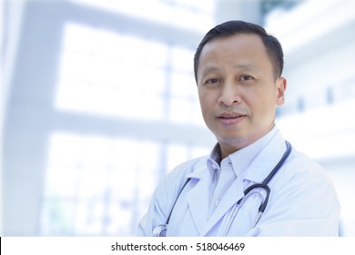 Asian Male Doctor With A Happy Smile On Blurry White Background