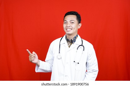 Asian Male Doctor Pointing On Blank Space Isolated Red Background