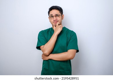 Asian male doctor in scrubs looking for idea thinking, searching for solution, standing white background pondering - Powered by Shutterstock