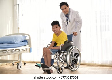 An Asian Male Doctor Taking Care And Look After Disabled Boy Patient /cripple Who Can Not Help Himself Sitting On Wheelchair In Hospital/Disability