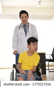 An Asian Male Doctor Taking Care And Look After Disabled Boy Patient /cripple Who Can Not Help Himself Sitting On Wheelchair In Hospital/Disability