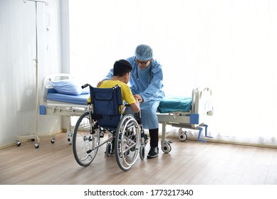 An Asian Male Doctor Taking Care And Look After Disabled Boy Patient /cripple Who Can Not Help Himself Sitting On Wheelchair In Hospital/Disability