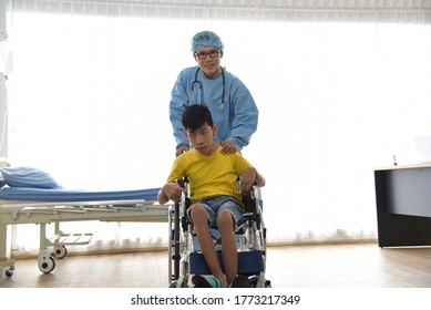 An Asian Male Doctor Taking Care And Look After Disabled Boy Patient /cripple Who Can Not Help Himself Sitting On Wheelchair In Hospital/Disability