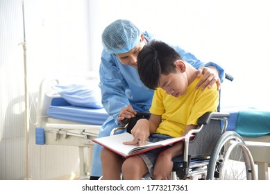 An Asian Male Doctor Taking Care And Look After Disabled Boy Patient /cripple Who Can Not Help Himself Sitting On Wheelchair In Hospital/Disability