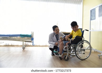 An Asian Male Doctor Taking Care And Look After Disabled Boy Patient /cripple Who Can Not Help Himself Sitting On Wheelchair In Hospital/Disability