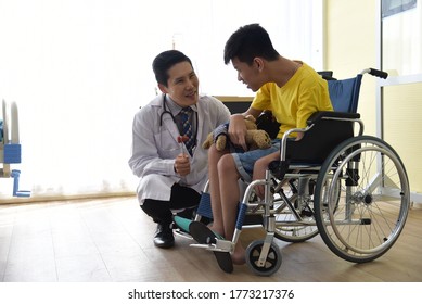 An Asian Male Doctor Taking Care And Look After Disabled Boy Patient /cripple Who Can Not Help Himself Sitting On Wheelchair In Hospital/Disability