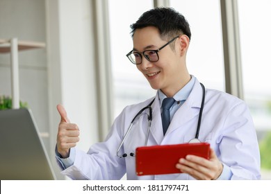 Asian Male Doctor Talking And Looking To Camera In Video Conference ,Positive Doctor Waving And Having Online Consultation On Digital Tablet Laptop