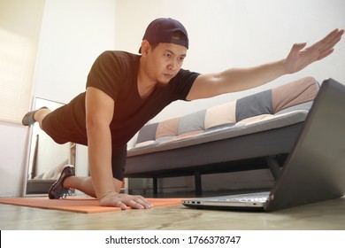 Asian Male Doing Exercise At Home While Watching Online Video Instruction On Laptop, Indoor Home Workout Concept, Keep Healthy On New Normal Lifestyle