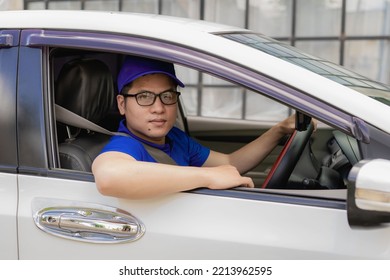 Asian Male Driver In A Blue Shirt, Hat, Glasses, Driving A Car